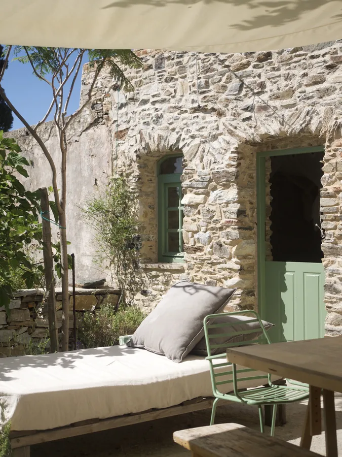 The stone façade, its green door and a daybed on the terrace