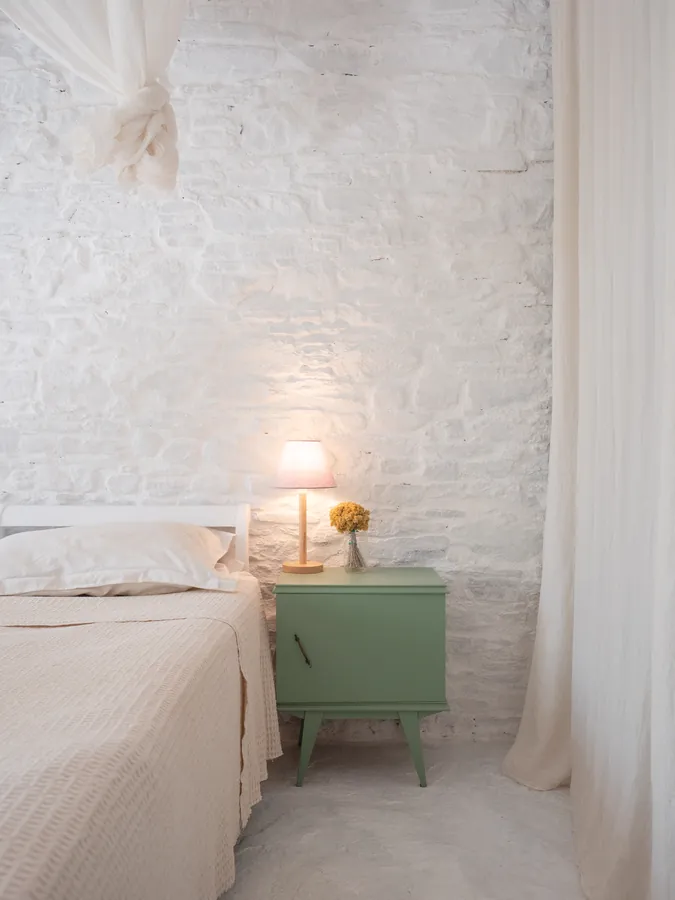 A bedroom with a green bedside table