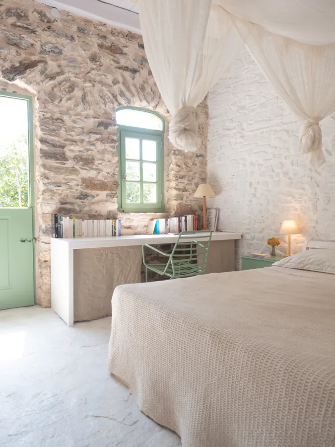 A bedroom with a desk and a green window